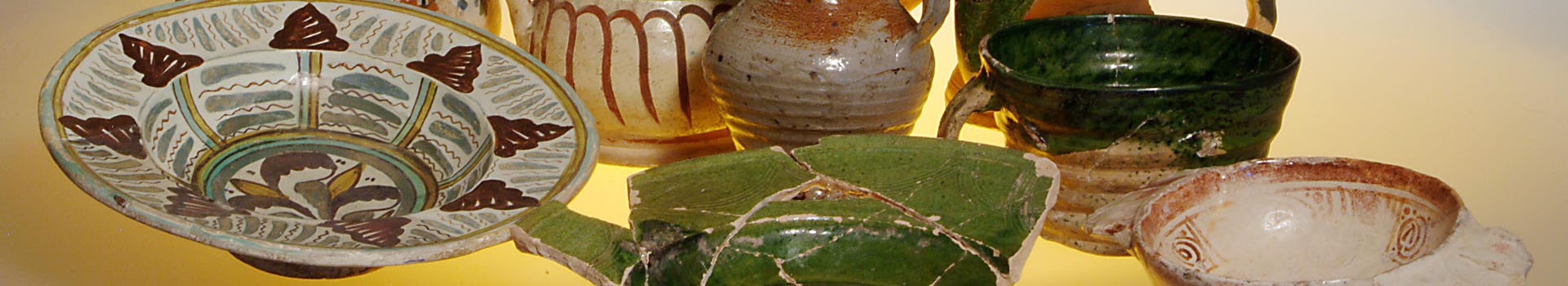 A selection of medieval ceramic jugs and plates stand on display.