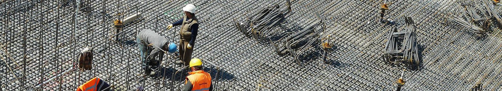 Members of a construction crew stand amongst metal reinforcements.