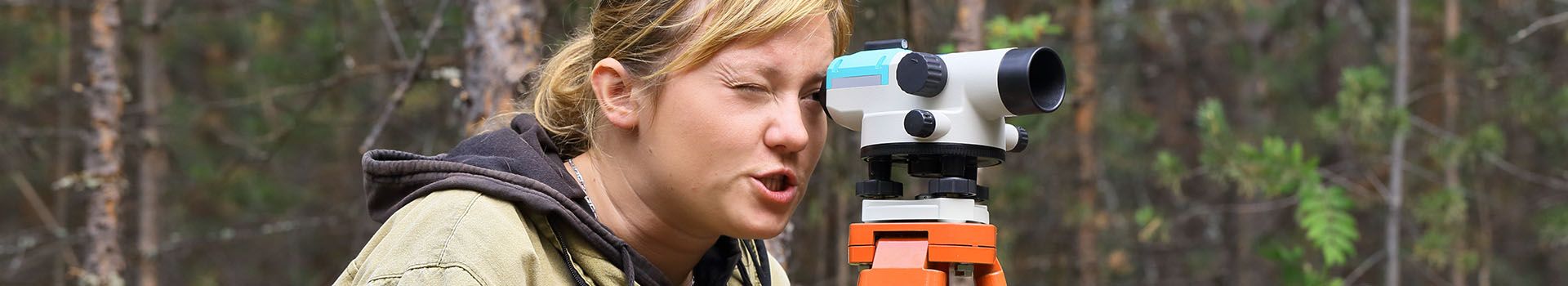 An archaeologist looks through a level mounted on a tripod.