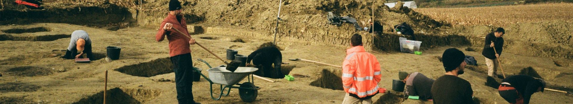 People standing looking at the work on a sandy site