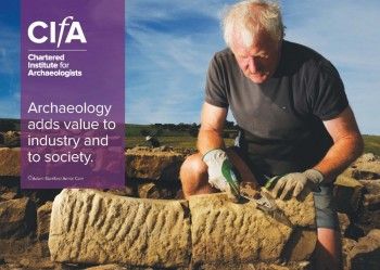 An archaeologist kneels next to an ancient carved stone.