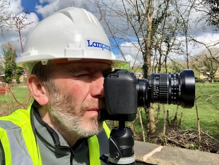 Karl Taylor looks through the viewfinder of a digital camera.