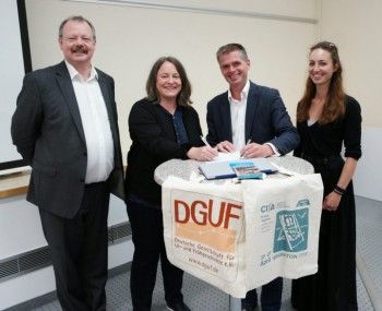 Representatives of CIfA and DGUF stand at a table to sign a document.