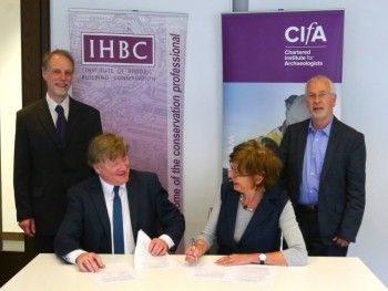 Representatives of CIfA and IHBC sit at a table to sign documents.