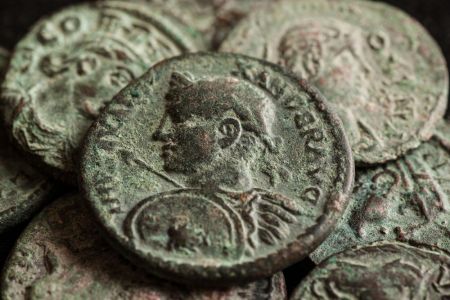 A selection of grey/green coloured Roman coins against a black background..