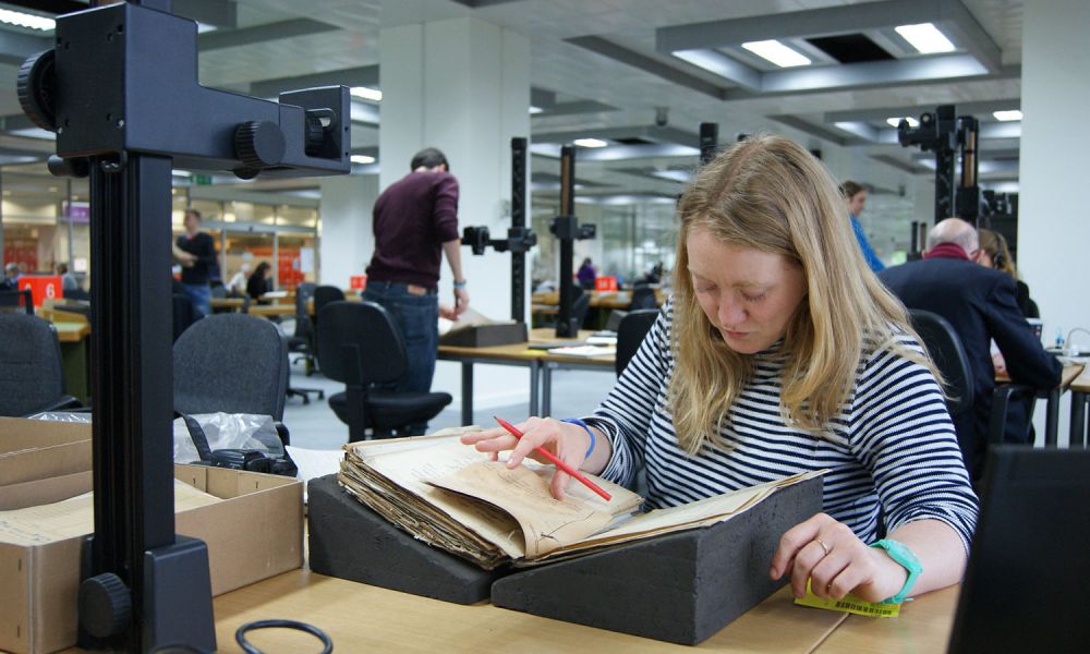 An archaeologist undertakes research on a old document in an archive.