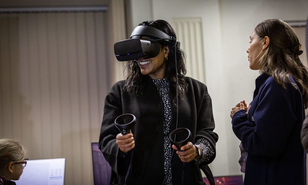 A woman wearing a VR headset smiles during a demonstration.