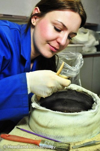 An archaeologist works with pottery fragments in a lab.