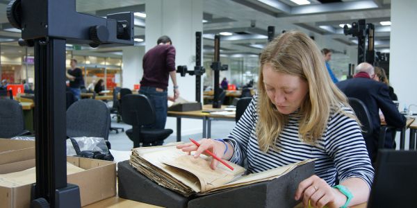 An archaeologist undertakes research on a old document in an archive.