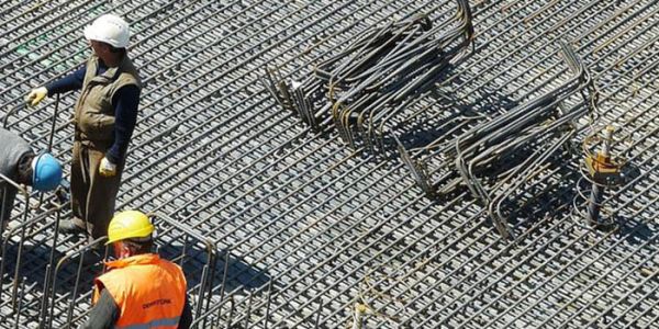 Members of a construction crew stand amongst metal reinforcements.