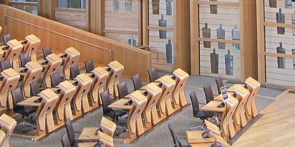 A council chamber built in light-coloured wood with tiered seating and large glass windows.