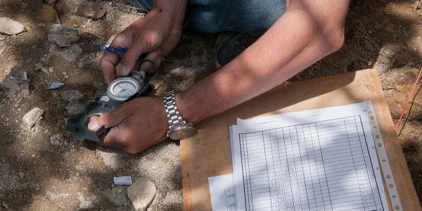 An archaeologist holds a compass whilst recording an archaeological feature.