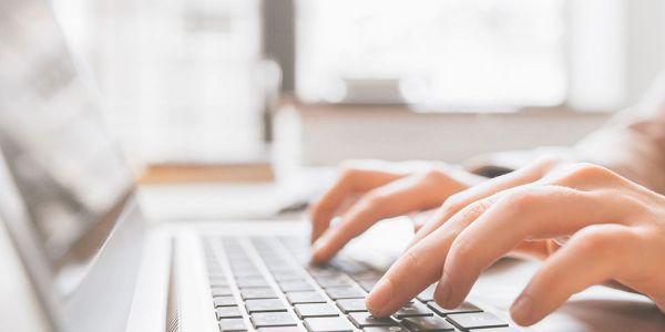 Hands type on a laptop's keyboard.