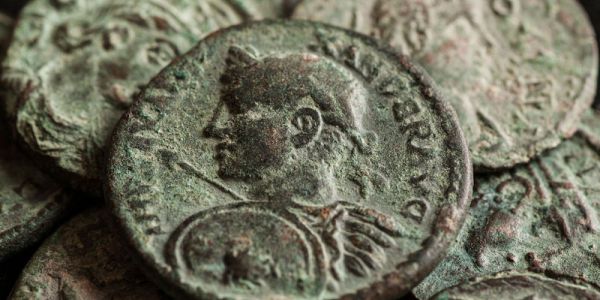 A selection of grey/green coloured Roman coins against a black background..