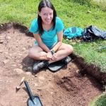 Photograph of Hayley Hayes sat cross-legged in an excavated slot